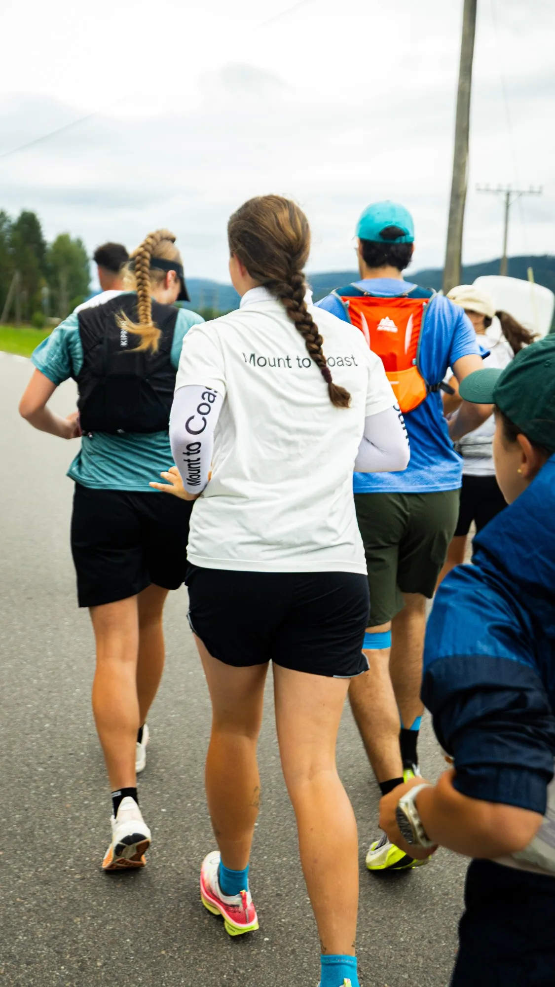 Runners in Mount to Coast shirts running down a road together